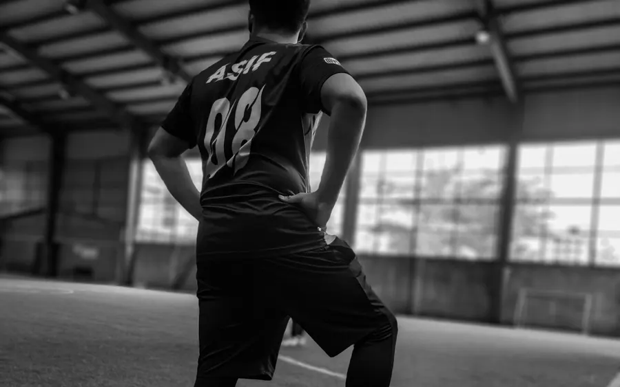 Jugador con el pie sobre el balón en una cancha techada, actitud de concentración