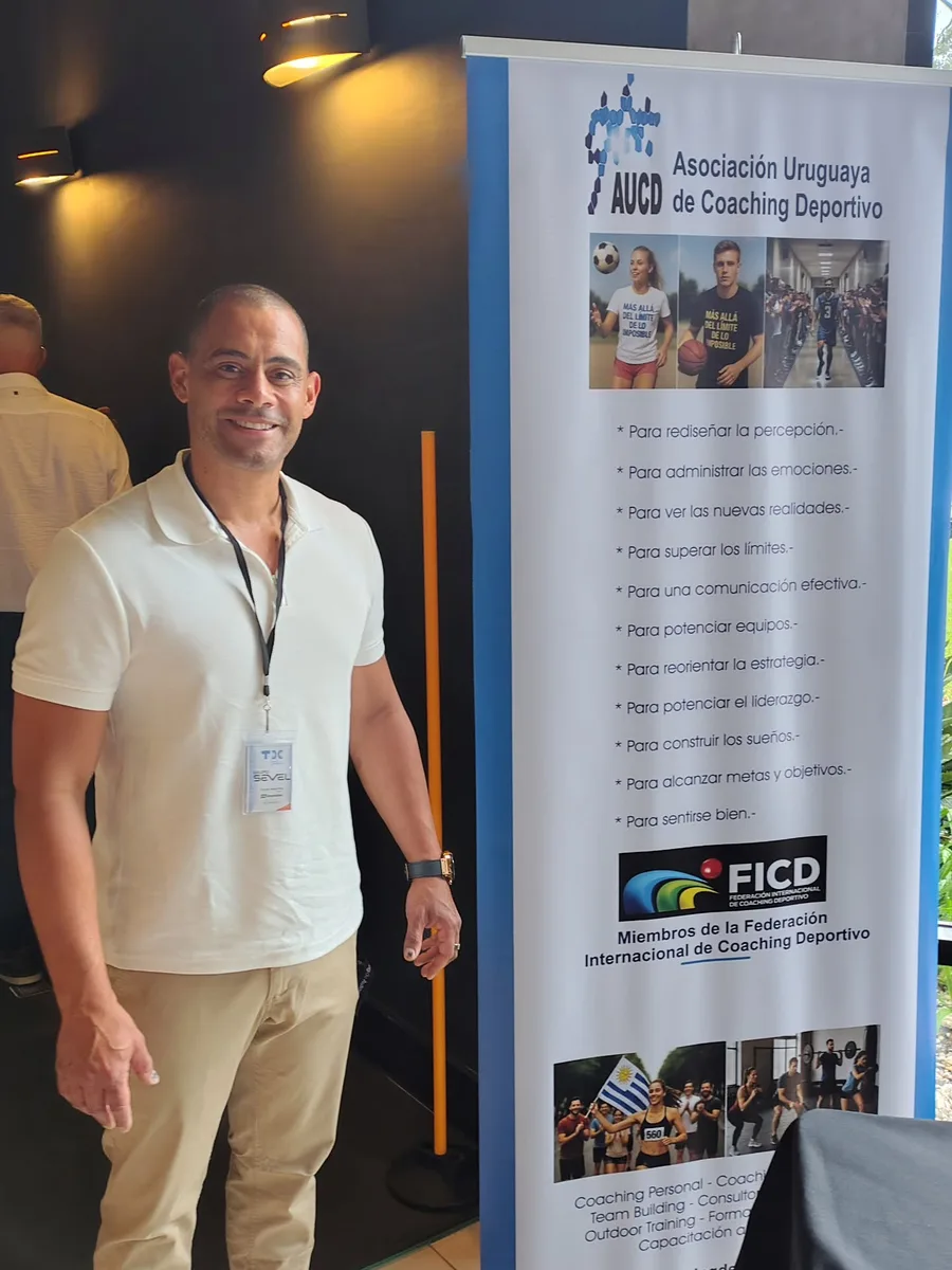 Sergio Valle Martínez junto al banner de la Asociación Uruguaya de Coaching Deportivo, miembro de la Federación Internacional de Coaching Deportivo