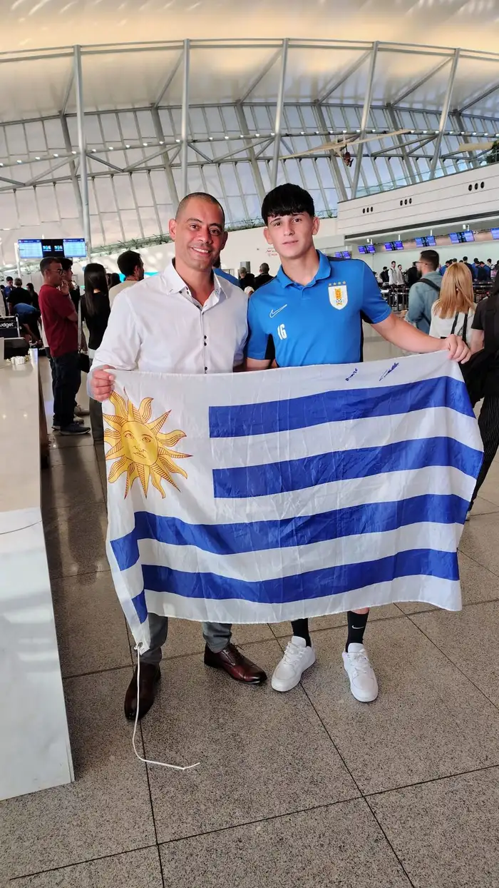 Sergio Valle Martínez junto a un jugador juvenil de la selección uruguaya, bandera de Uruguay